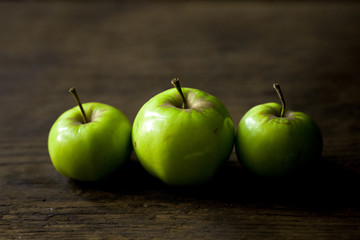 Green organic healthy apples in bowl on wooden board. Healthy food