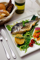 grilled dorado with lemon served with greens and salad bread and wine