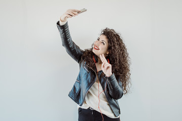 pretty young woman with curly hair listening to music and taking selfie