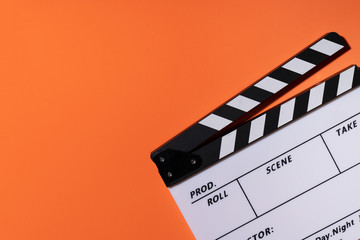 Fototapeta na wymiar movie clapper on orange table background ; film, cinema and video photography concept