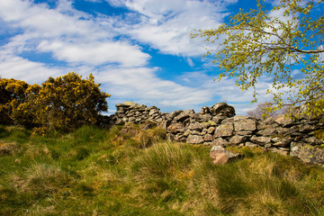 An old wall on the top of a fell with blue sky and clouds.