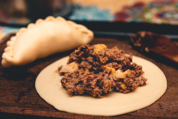 La tradicional empanada de carne argentina, sus ingredientes,  como primer plano sobre una tabla de madera rústica.