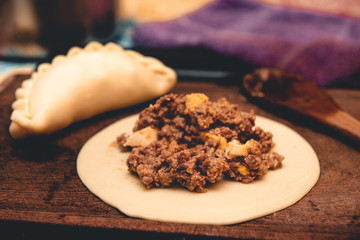 La tradicional empanada de carne argentina, sus ingredientes,  como primer plano sobre una tabla de madera rústica.