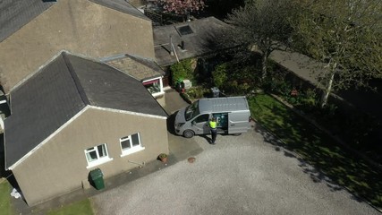 4K: Aerial Drone Shot - Grocery delivery driver from Supermarket lifts a crate of food out of the van - He is wearing a face mask.Stock Video Clip Footage - Powered by Adobe