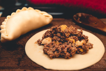La tradicional empanada de carne argentina, sus ingredientes,  como primer plano sobre una tabla de madera rústica.