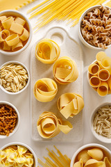 Different types of pasta on a white background, top view