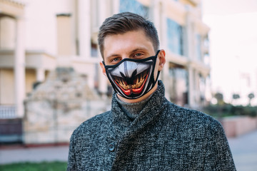 A handsome young man in a black mask  with stylish pattern for protection from coronavirus infection - 342416770