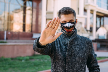 The guy wearing a black mask  with stylish pattern to protect against virus Covid-19 shows a hand gesture stop for stop coronavirus outbreak - 342416909