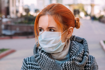 Street portrait of a young woman wearing protective medical mask during coronavirus pandemic - 342416992