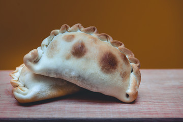 La tradicional empanada de carne argentina, sus ingredientes,  como primer plano sobre una tabla de madera rústica.