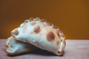 La tradicional empanada de carne argentina, sus ingredientes,  como primer plano sobre una tabla de madera rústica.