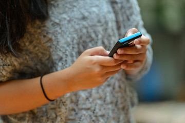 Hands of young woman using phone outdoors