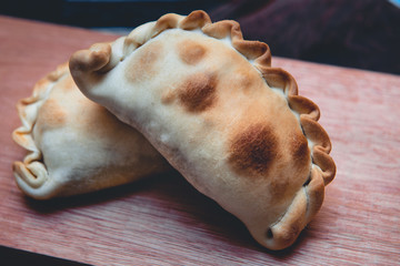 La tradicional empanada de carne argentina, sus ingredientes,  como primer plano sobre una tabla de madera rústica
