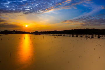Silhouette of lifestyle of fisherman in the evening with sunset in Thailand. Sunset with sea and mangrove forest. Mangrove forest, fishing net, river. Asia, Chanthaburi Province, Thailand.