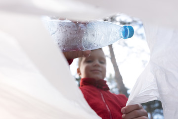 child bends a plastic bottle into a bag. garbage collection, pollution of the planet