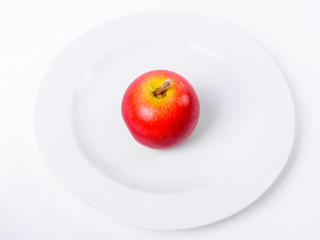 Red Apple On White Plate Against White Background