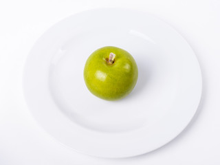 Green Apple On White Plate Against White Background