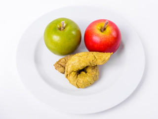 Red And Green Apple With Artificial Poo On White Plate