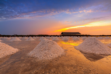 Fototapeta na wymiar A collection of sea salt that has been collected for sale in the salt farm in the atmosphere of the golden light of the setting sun in central Phetchaburi province of Thailand.