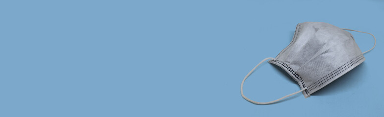One white protective face mask to prevent fast spreading coronavirus on blue background. Banner style with copy space and mockup for text.