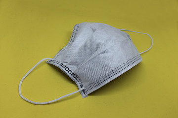 One protective white face mask to prevent fast spreading coronavirus on yellow background, square.