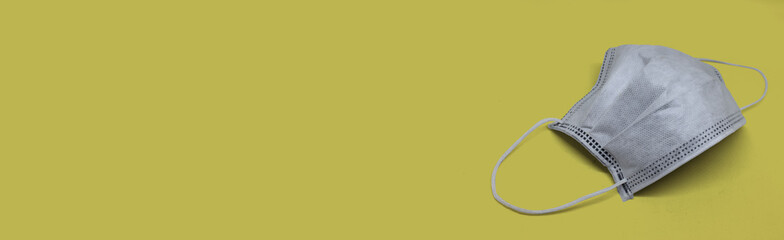 One white protective face mask to prevent fast spreading coronavirus on yellow background. Banner style with copy space and mockup for text.