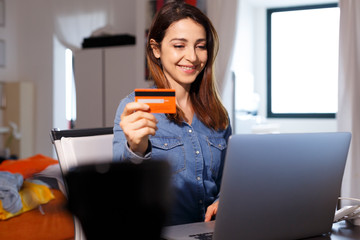 Donna sorridente con i capelli lunghi utilizza la sua carta di credito per fare un ordine...