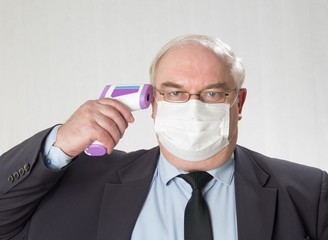 Close up portrait of handsome man in a protective medical mask  and glasses with IR thermometer