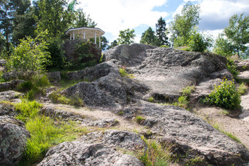 Rocky road up to the white gazebo. Cloudy weather on a summer day.