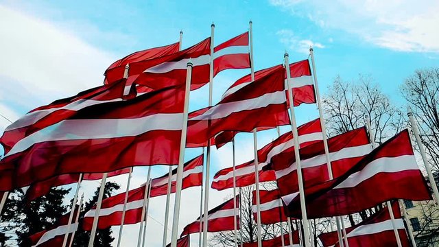 latvian flags attached to a pole waving in the wind, the skyline of Riga, Latvia, concept of travel