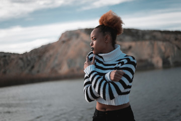 black woman in the middle of a field during sunset, wearing a black and white striped sweater