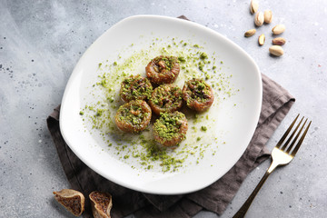 Eastern desserts. Vegan sweetness. Dried figs with walnuts and pistachio crumbs on a white plate on a light grey background with a fork. Menu restaurant. Background image, copy space