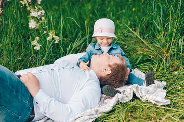 Father and his little daughter spend a nice time together. A family walks on the grass in a flowered garden.