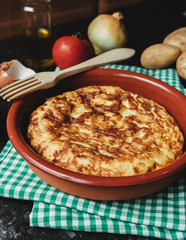 Spanish potato omelette on a clay plate with a wooden fork. Homemade fresh omelette