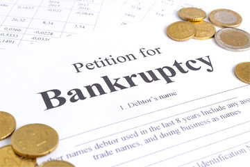 Close-up bancruptcy petition and golden coins. Application form.