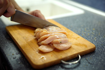woman cutting chicken fillet