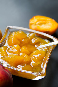 Homemade Delicious Peach And Vanilla Jam In A Glass Ramekin With A Silver Spoon. Dark Background. Back View. 