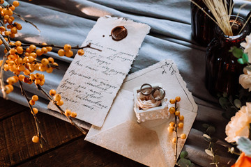 Wedding rings and decor in autumn vintage style close-up. Orange colors and romantic letter.