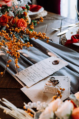 Wedding rings and decor in autumn vintage style close-up. Orange colors and romantic letter.