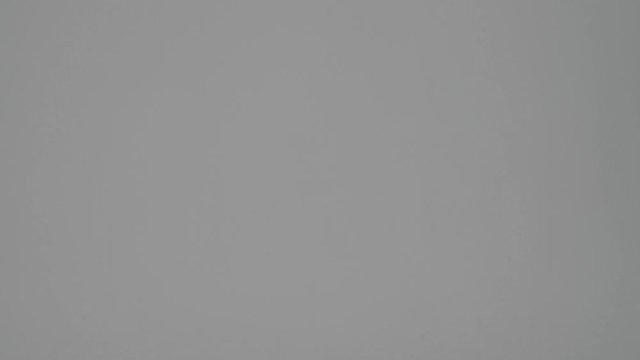 A pretty young woman is grabbed herself to the neck and showed choking isolated over a grey background in studio