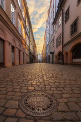 Fototapeta premium Old narrow street in Prague, paving stones at sunset