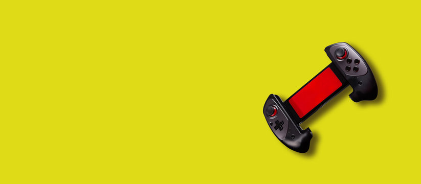 Gamepad Banner. Console For Phone Hanging In Air On Vibrant Yellow Background. Smartphones Games Concept. Copy Space.