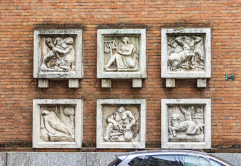Stone bas-reliefs with the image of the zodiac signs on the wall of Teatro Romano theater building on Piazza degli Affari square in Milan, Italy.