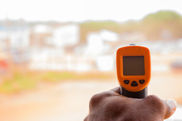 Close-up shot of a man ready to use infrared forehead thermometer (thermometer gun) to check body temperature for virus symptoms - epidemic virus outbreak concept