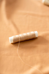 Sewing background with tailor equipment on the peach colored cloth. Selective focus.
