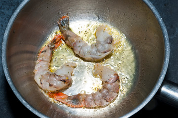 Cooking tiger prawns in a pan shot close-up.
