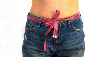 female body in jeans with a pink centimeter tied in a bow like a belt on a white background