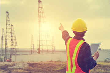 Engineer use tablet device standing at construction building background on morning
