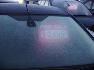 For Sale sign inside car on used car lot, frosty morning, England.