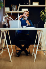 Young innovative dedicated bearded employee sitting in his modern office and drawing sketches of windmills. Sustainable development concept.